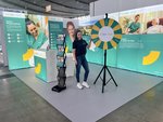Der Messestand von leben&wohnen mit einem Glücksrad und einer Mitarbeiterin