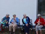 Vier Seniorinnen sind sitzen draußen auf Gartenstühlen