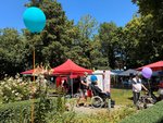 Der Garten des Filderhofs mit roten Sonnenschirmen und einem Luftballon im Vordergrund. Bewohnende gehen durch den Garten.