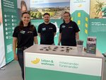 Zwei Mitarbeiterinnen und ein Mitarbeiter am Messestand