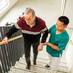 Ein Pfleger unterstützt einen Senior beim Treppenlaufen..