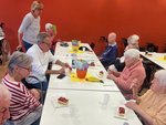 Bewohnende sitzen an einer gedeckten Tafel mit Kuchen und Mineralwasser