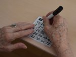 Hände einer älteren Person machen gerade ein Kreuz auf einer Bingo-Tafel