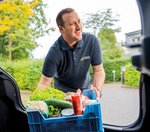 Ein Mitarbeiter des Ambulanten Dienstes lädt eine Kiste mit Lebensmitteln aus dem Auto. 