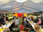 Bewohnende sitzen im Festzelt an gedeckten Tafeln