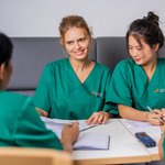 Das Pflegepersonal sitzt an einem Tisch und bespricht sich. 