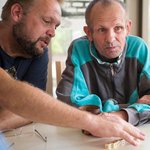 Ein Sozialarbeiter spielt ein Würfelspiel mit einem Bewohner. 