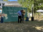 Eine herzliche Umarmung des Geschäftsführers mit der Einrichtungsleiterin, die einen Blumenstrauß in der Hand hält.