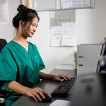 Eine Pflegerin sitzt am Rechner und arbeitet. 