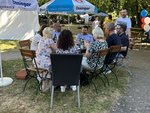 Gemeinsames Beisammensitzen von mehreren Personen der Gäste an einem Tisch mit Sonnenschirm im Garten des Parkheim Bergs.