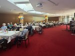 Die Bewohnenden sitzen im Saal an Tischen im Hans Rehn Stift