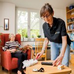 Eine Hauswirtschafterin wischt Staub bei einer Bewohnerin.